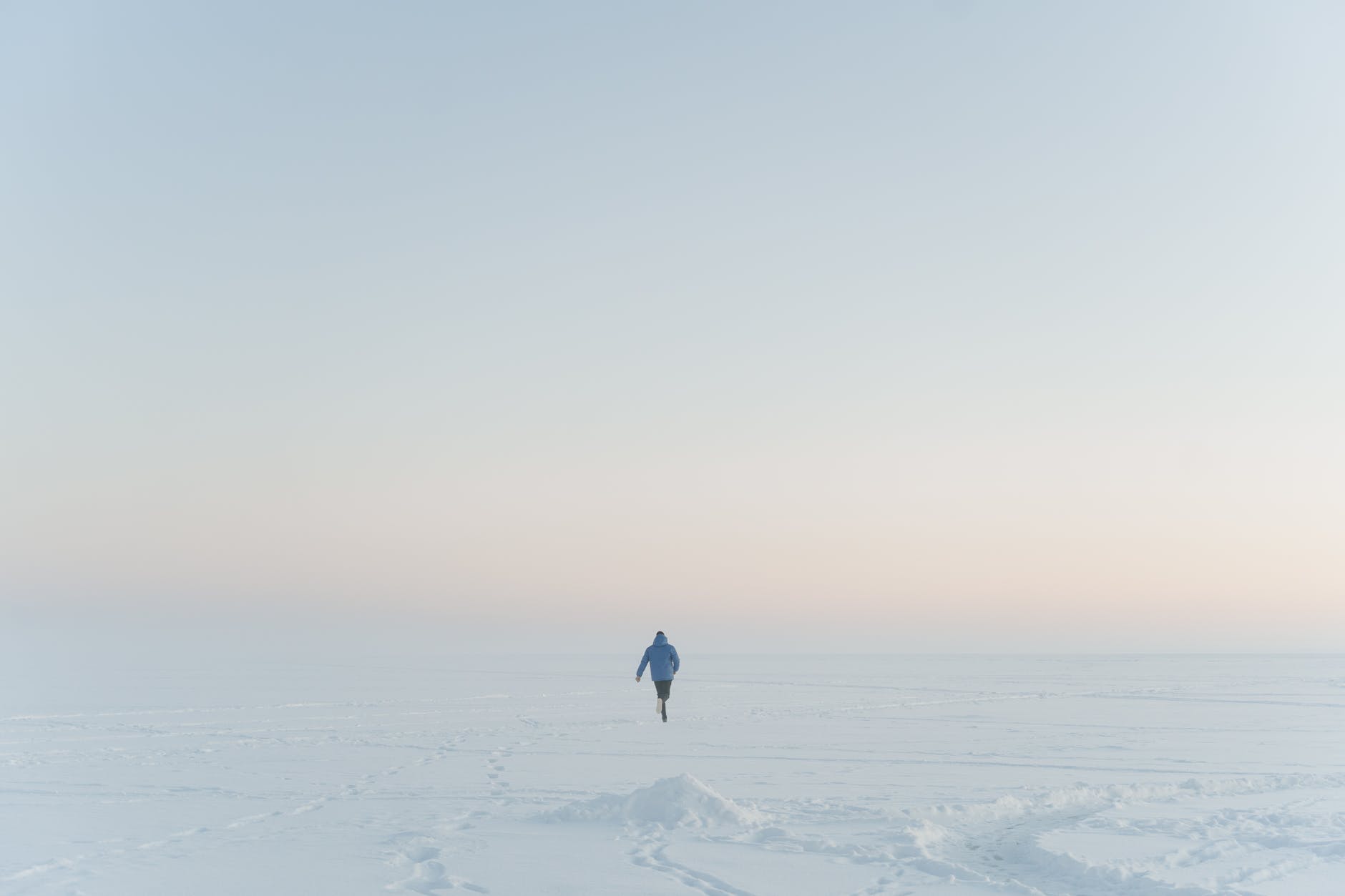 person in jacket running on snow covered ground